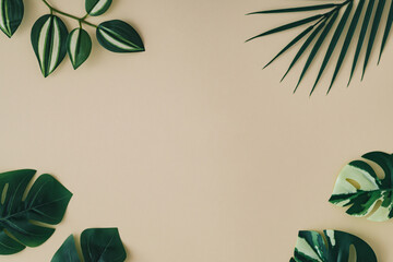 Summer scene with green tropical leaves on sand color background. Minimal concept. Creative copy...