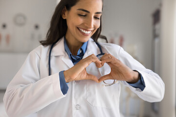 Symbol of love and hope. Beautiful smiling young woman doctor cardiologist medical professional...