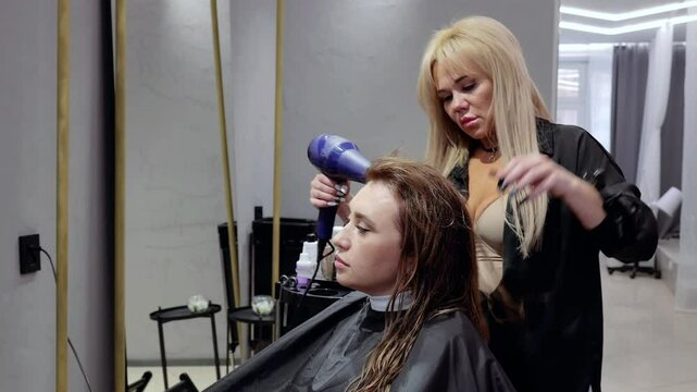 Hairstylist expertly blow drying hair, carefully styling a client in a chic, contemporary salon setting, showcasing skilled hair care techniques
