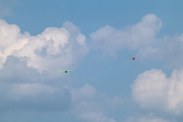 Green and Red Aeroprakt Ukrainian ultralight aircraft planes in cloudy blue sky on airshow