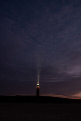 Obraz premium Eierland, De Cocksdorp, Texel, The Netherlands, Oktober 28th, 2024, A splendid lighthouse beams its bright light across the tranquil, dark sky at dusk, signifying guidance and safety