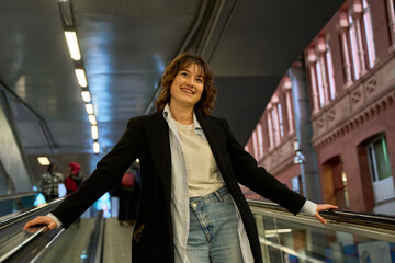 Young professional woman going up on escalator in modern building