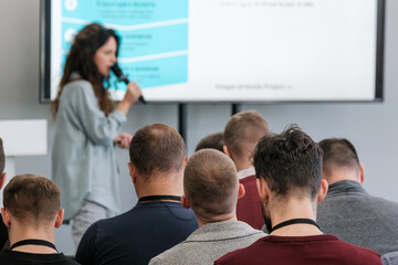 Business seminar speaker engaging audience with presentation. Attendees focused on learning and...