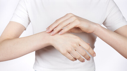 A young girl rubs cosmetic cream for care and moisturizing onto the skin of her hands.
