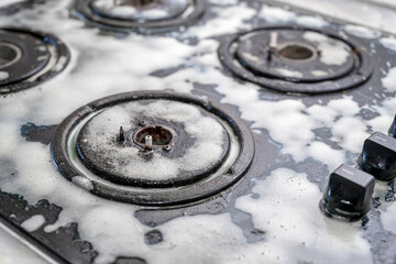 Obraz premium Cleaning a gas stove with kitchen utensils, household concepts, or hygiene and cleaning