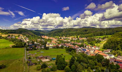 Vibrant German Village Nestled in a Valley Surrounded by Lush Greenery and Picturesque Mountains on a Bright Sunny Day