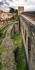 Medieval stone wall and tower with grass moat of Carcassonne Castle in the historic village.