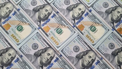 Close-up of multiple $100 bills arranged in a pattern. US currency background with Benjamin Franklin portrait. Finance and wealth concept for design and print.
