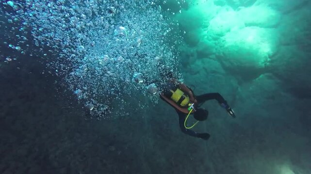 Underwater divers explore the seabed. Air bubbles rise up from the drivers