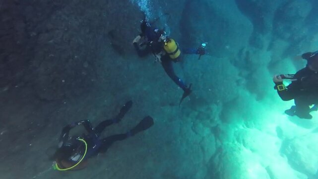 Underwater divers explore the seabed. Air bubbles rise up from the drivers