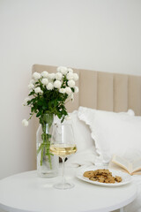 An Elegant Bedroom Setup Featuring Beautiful Flowers, a Candle, and a Glass of Wine