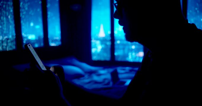 a man in an empty bedroom in the dark with his smartphone