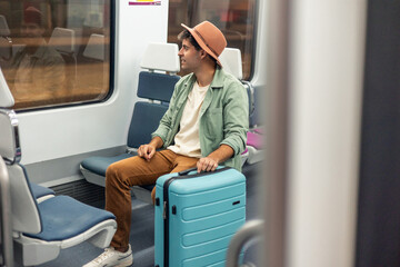 Fototapeta premium latin Tourist traveling by train holding his suitcase and looking out the window