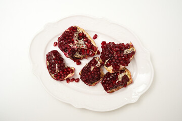 Ripe pomegranate fruits on white plate.