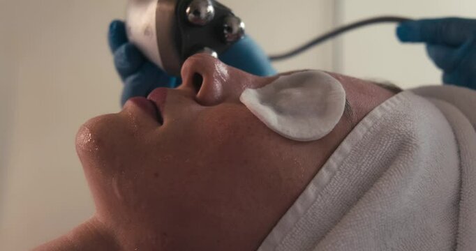 A woman receiving a radiofrequency facial treatment at a beauty clinic. The procedure helps with skin tightening, anti-aging, and rejuvenation, promoting a youthful appearance