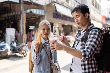 Couple enjoying snacks and drinks at a lively street market.