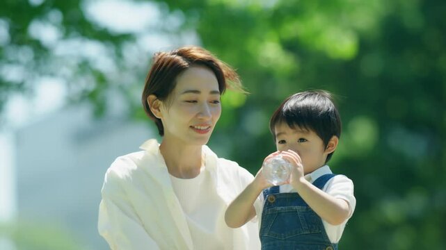 3歳の息子に水を飲ませる母親