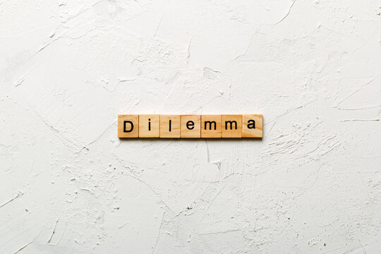 Dilemma word written on wood block. Dilemma text on cement table for your desing, concept