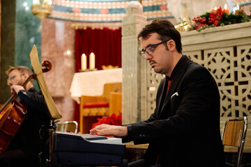 Musicians perform during a concert in a church with festive decorations