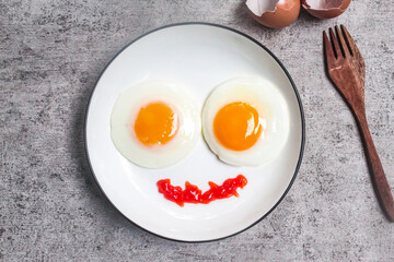 a plate of fried eggs with sauce in the shape of a smiley face