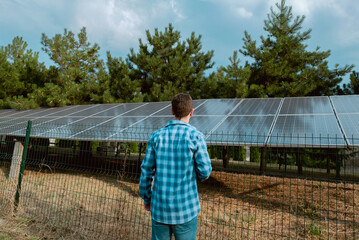 Engineer standing with his back, calculating the optimal placement and tilt of solar panels for...