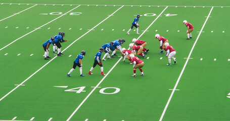Two American Football Teams Stand Across From Each Other on the Line of Scrimmage as the Ball is Ready to be Passed to Start the Game. Gridiron Players Ready to Tackle and Defend