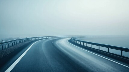 Fototapeta premium A winding road disappears into a foggy landscape, creating a serene and mysterious atmosphere.