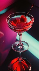 Bright red non-alcoholic beverage with cherry sits on a reflective surface in an elegant setting