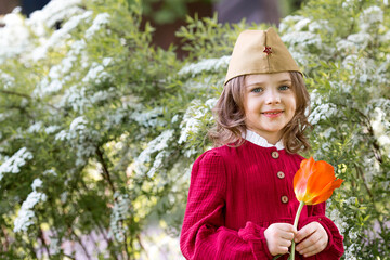 The concept of the May 9th holiday. Portrait of a beautiful girl in a military cap with a tulip...