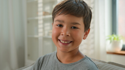 Happy little adorable Caucasian boy male child schoolboy cheerful looking at camera smiling close...