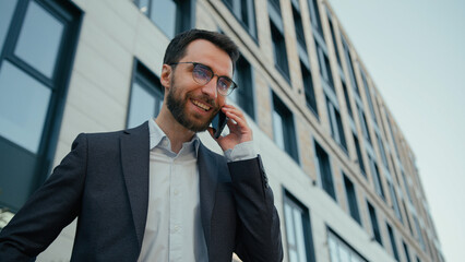 Joyful happy man Caucasian businessman talking mobile phone in city funny carefree conversation...