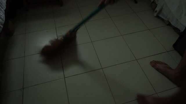 High angle wide view of traditional Filipino broom sweeping floor in Asian household.