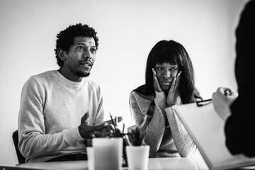 Fototapeta premium African american couple sitting at psychologist's office for a couples therapy - Couple relationship concept in trouble and crisis - Focus on man's face - Black and white editing