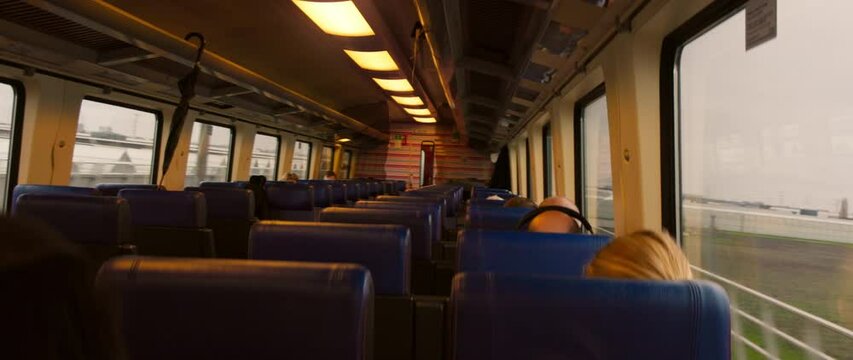 Inside of an empty train, there are blue seats complemented by large, expansive windows