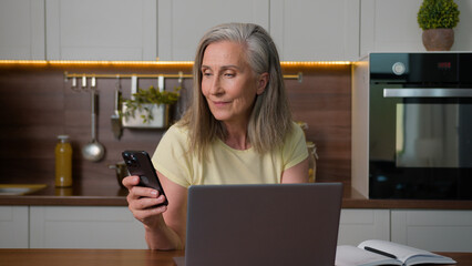 Mature 50s business woman wife online working with computer distance learning using laptop and...