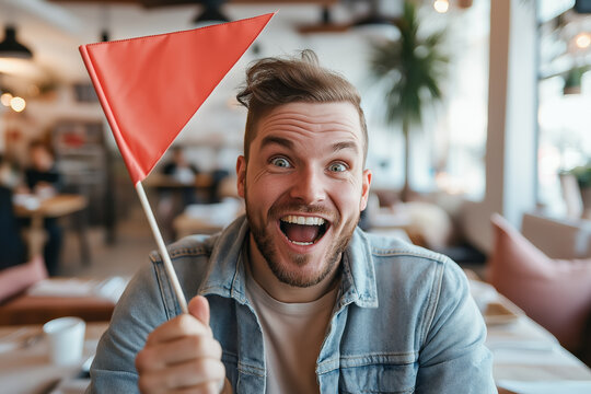 Man holding red flag in restaurant on a date, expressing excitement, representing red flags in dating and relationships.