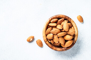 Almond nuts in wooden bowl at white background.