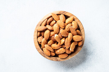 Almond nuts in wooden bowl at white background.