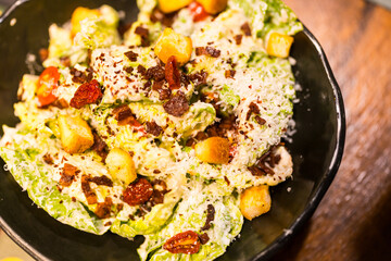 A bowl of fresh caesar salad with bacon, croutons and cheese