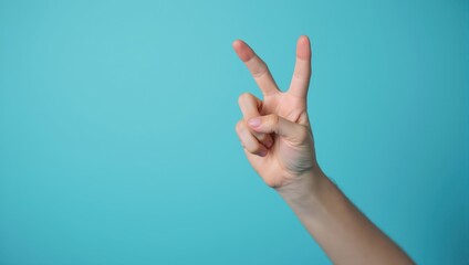 Human Hand Forming Peace Sign Against Teal Background