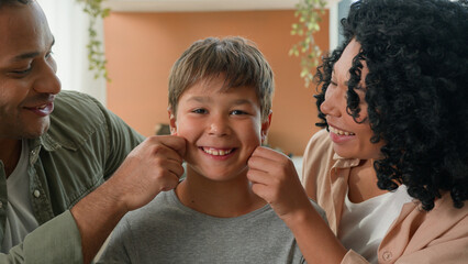 Multiracial family portrait loving African American parents father mother pinching cheeks of...
