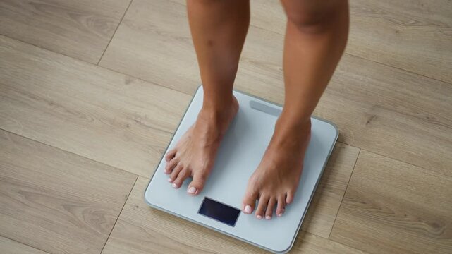 Video of of healthy young woman, happy to see that she has lost weight on scale weight at home