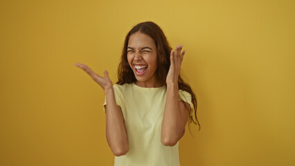 Young woman feeling joyful over an isolated yellow background, expressing happiness with wide smile...