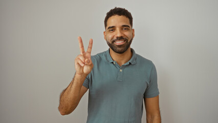 Young hispanic man holding peace sign smiling isolated against white wall for positive gesture