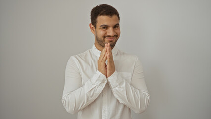 Young man smiling with clasped hands over white background