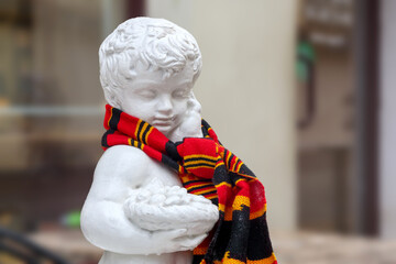 
a small plaster boy with a red scarf around his neck