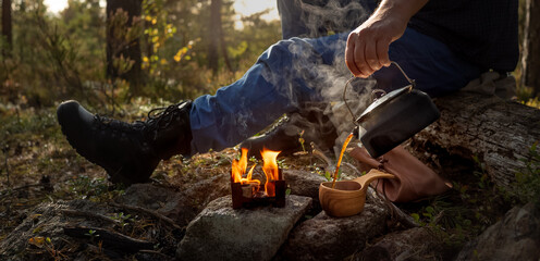 Hand pouring coffee into a wooden cup after having been made on a solid fuel portable stove