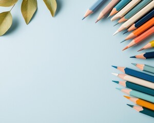 Colorful Pencils and Green Leaves on Soft Blue Background