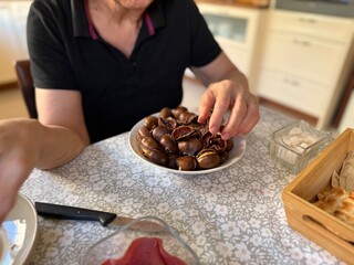 Old woman hands peeling roasted chestnuts