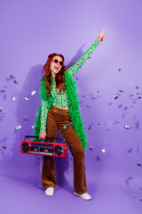Young woman with red hair poses joyfully with a boombox against a vibrant violet vertical backdrop